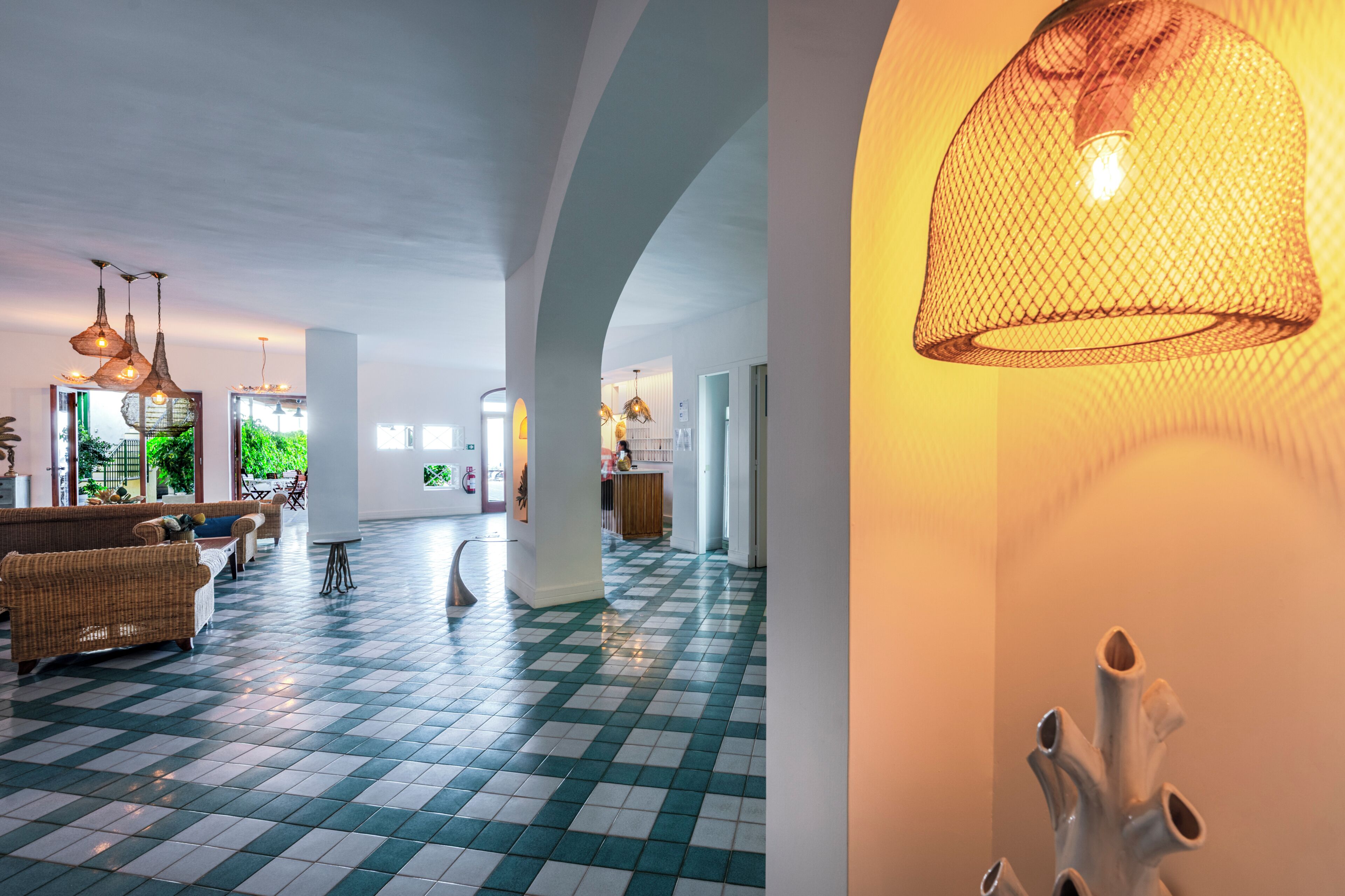 Un hall d’entrée spacieux, doté d’un sol à carreaux, de meubles en osier et de luminaires suspendus.