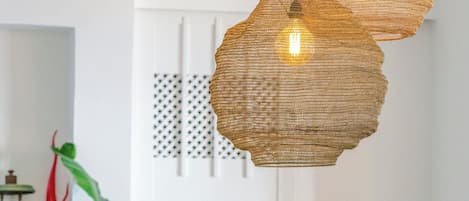 Une pièce avec un canapé en osier, une petite table en bois et des lampes en osier suspendues au plafond.