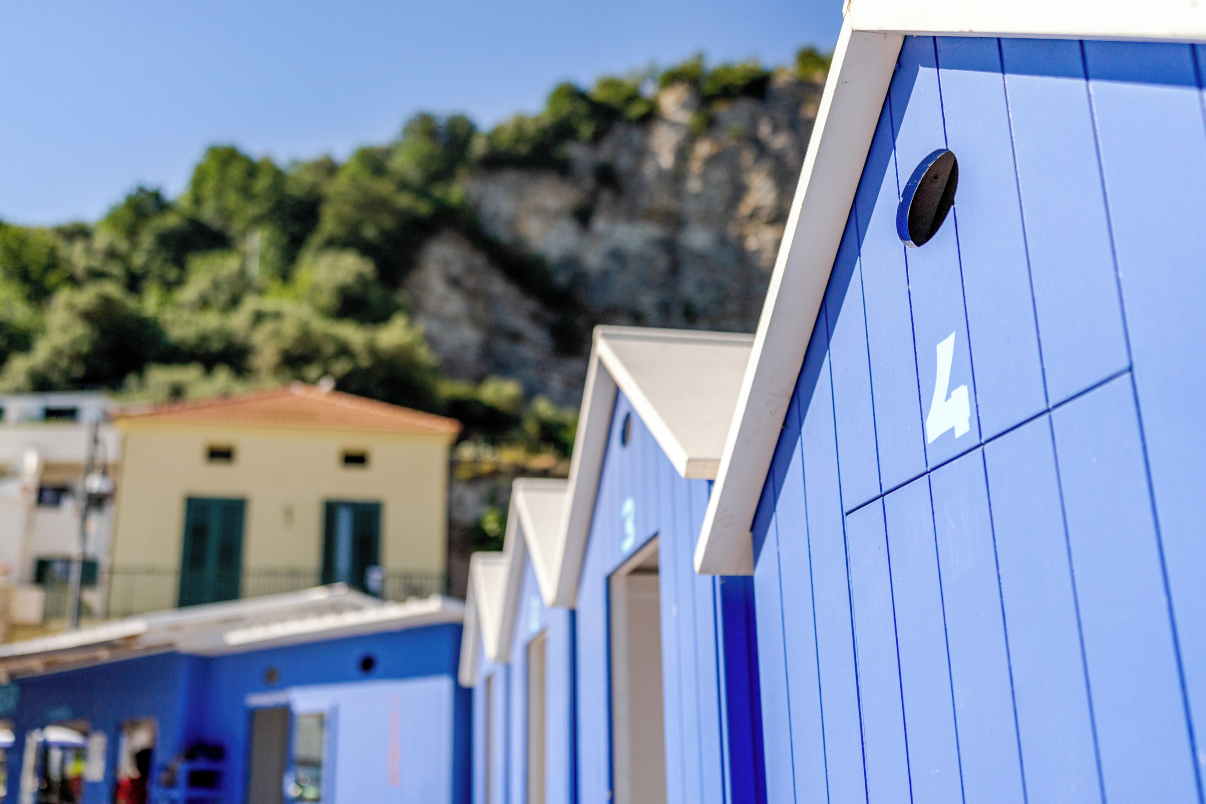 A row of blue buildings with a mountain in the background.
