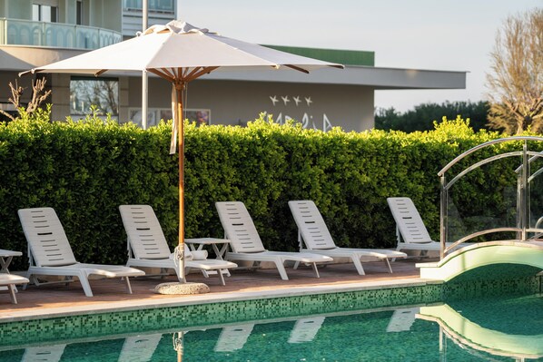 En säsongsöppen utomhuspool, parasoller och solstolar