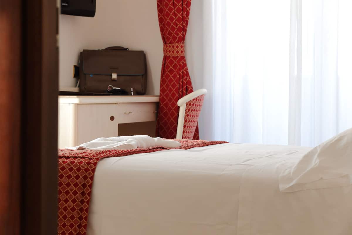 A hotel room with a bed, a desk, and a chair.