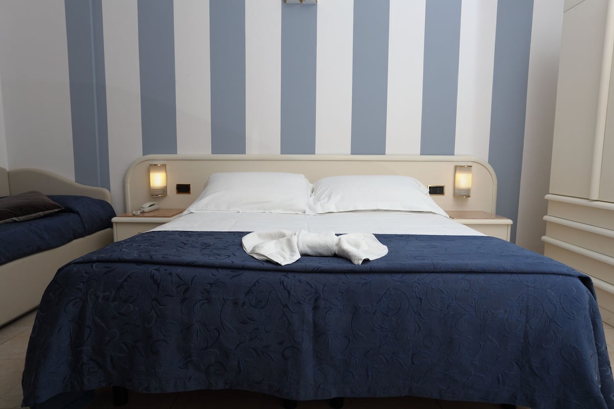 A hotel room with a bed, bedside tables, and a striped wall.