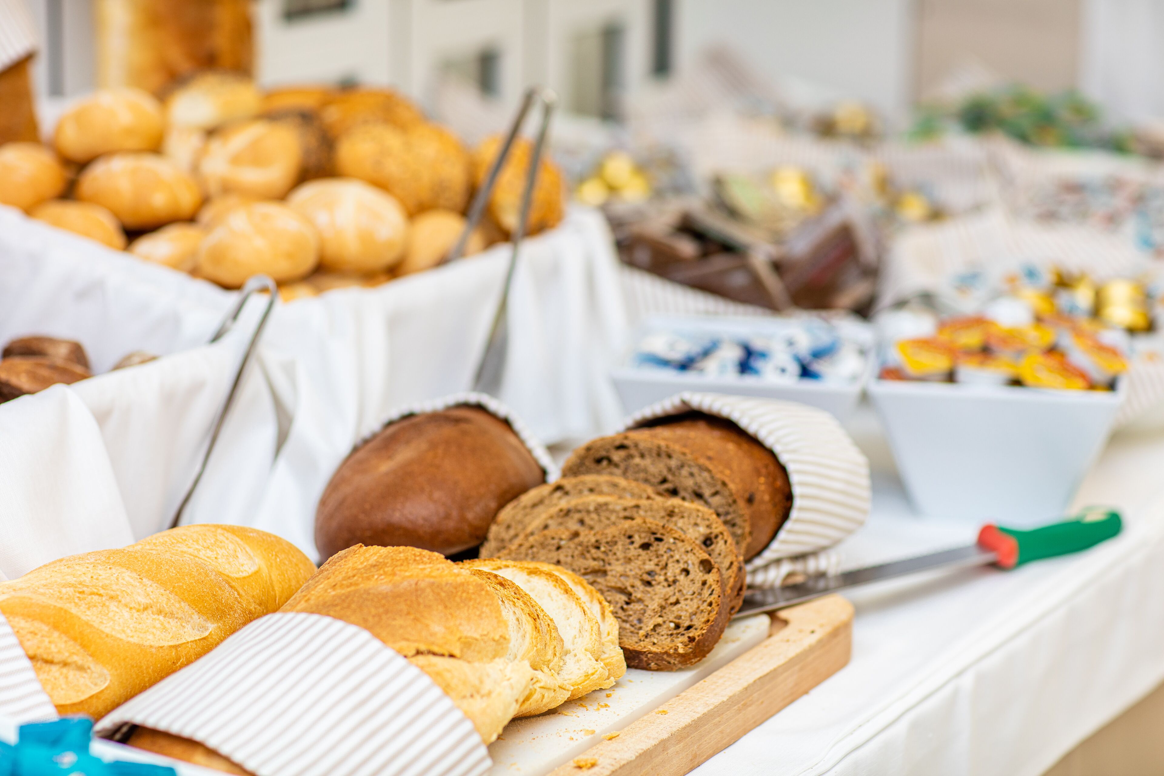 A variety of breads and pastries on a table, including sliced bread and rolls.