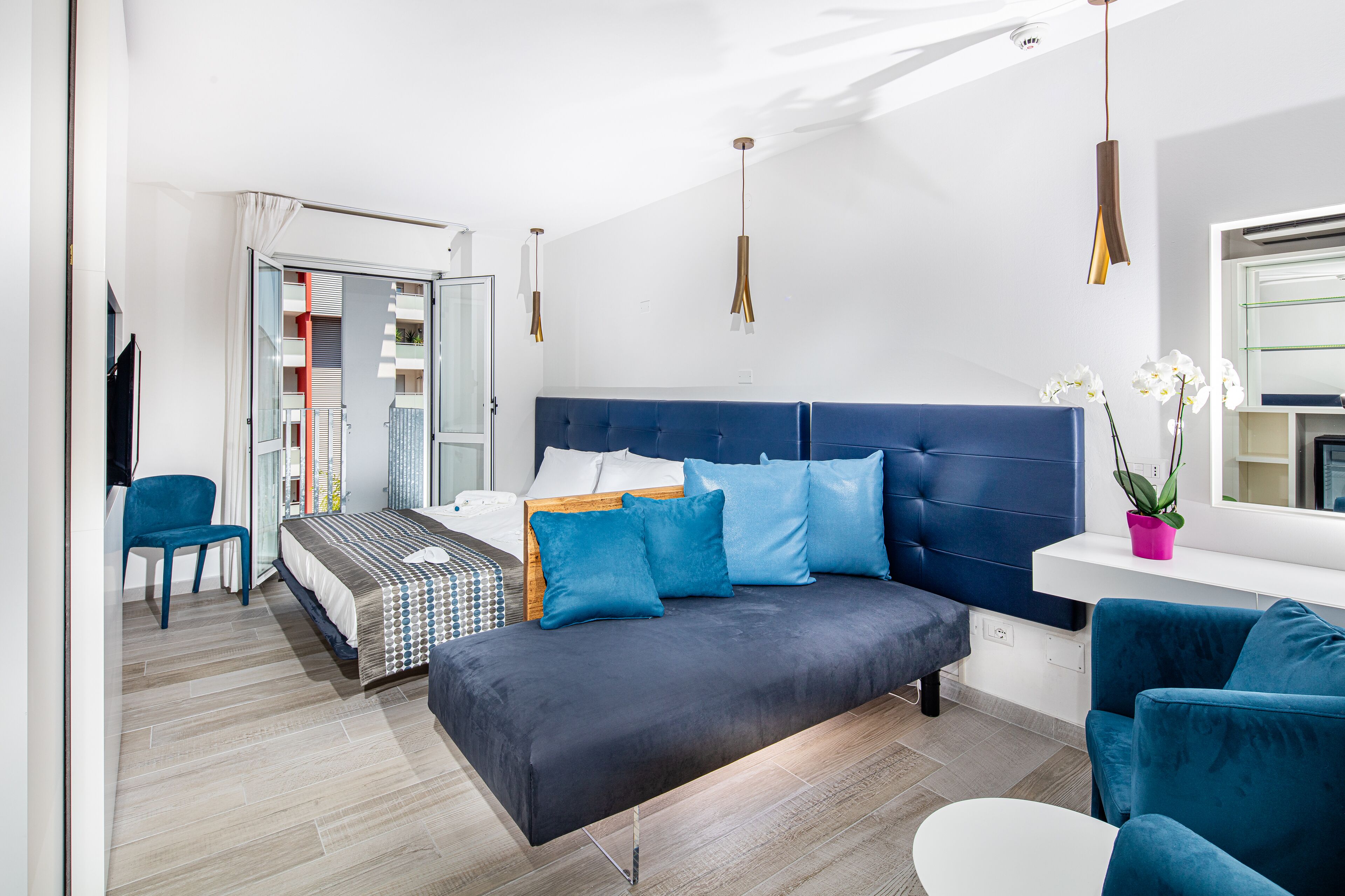 Ein modernes Schlafzimmer mit Bett, Sofa, Sessel und Schreibtisch.