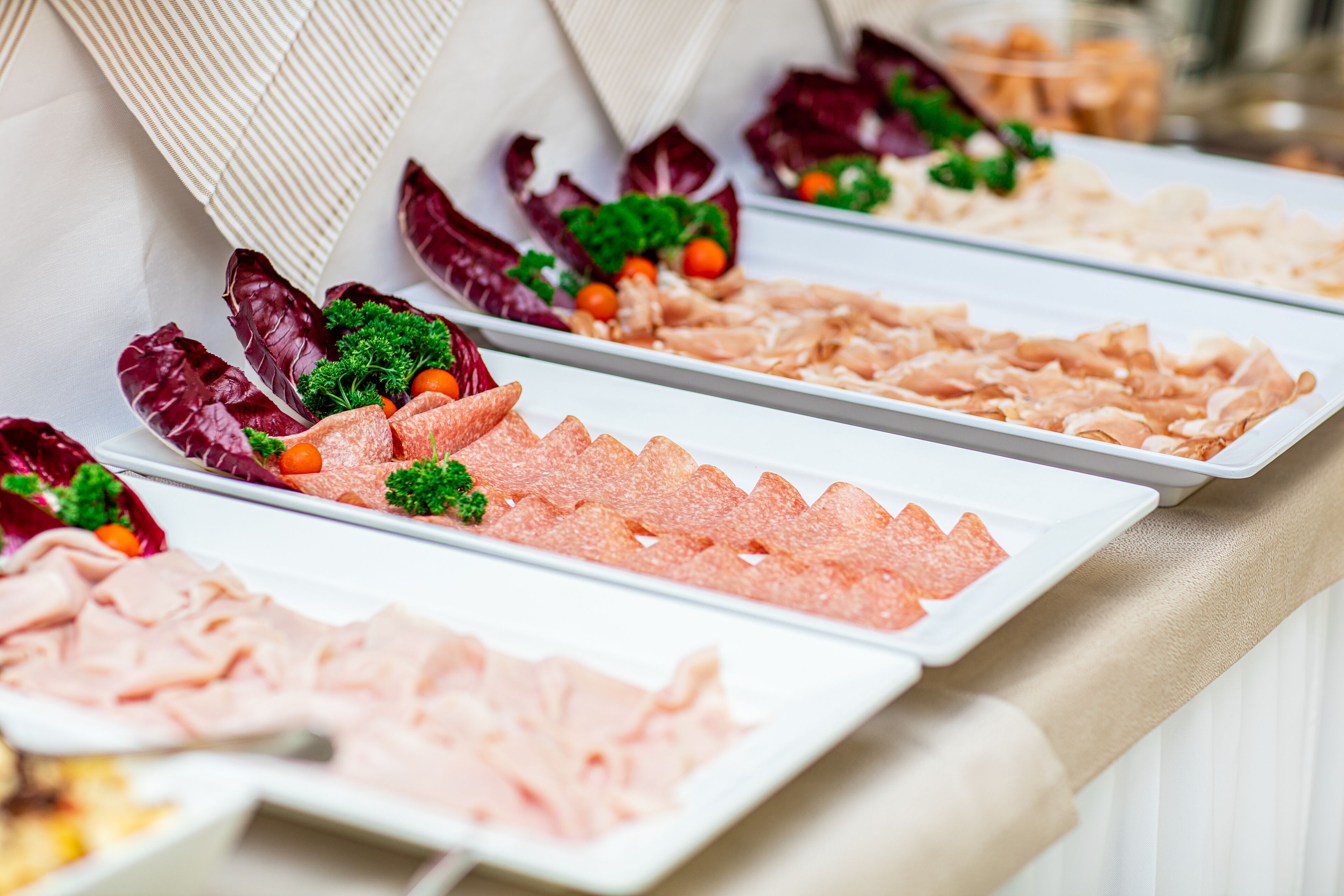 A buffet with various types of deli meats and garnishes.