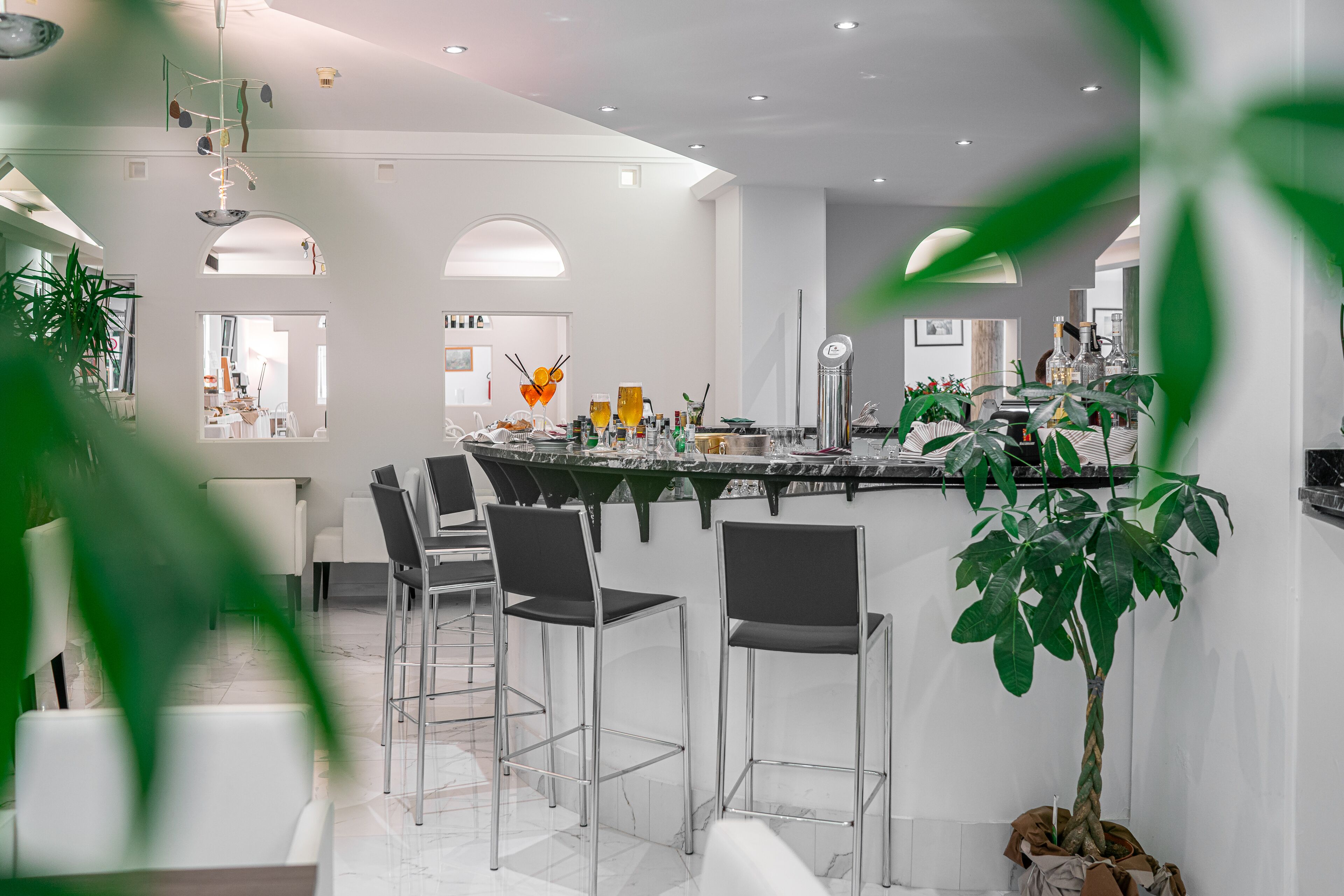 A modern kitchen with a marble countertop, bar stools, and a potted plant.