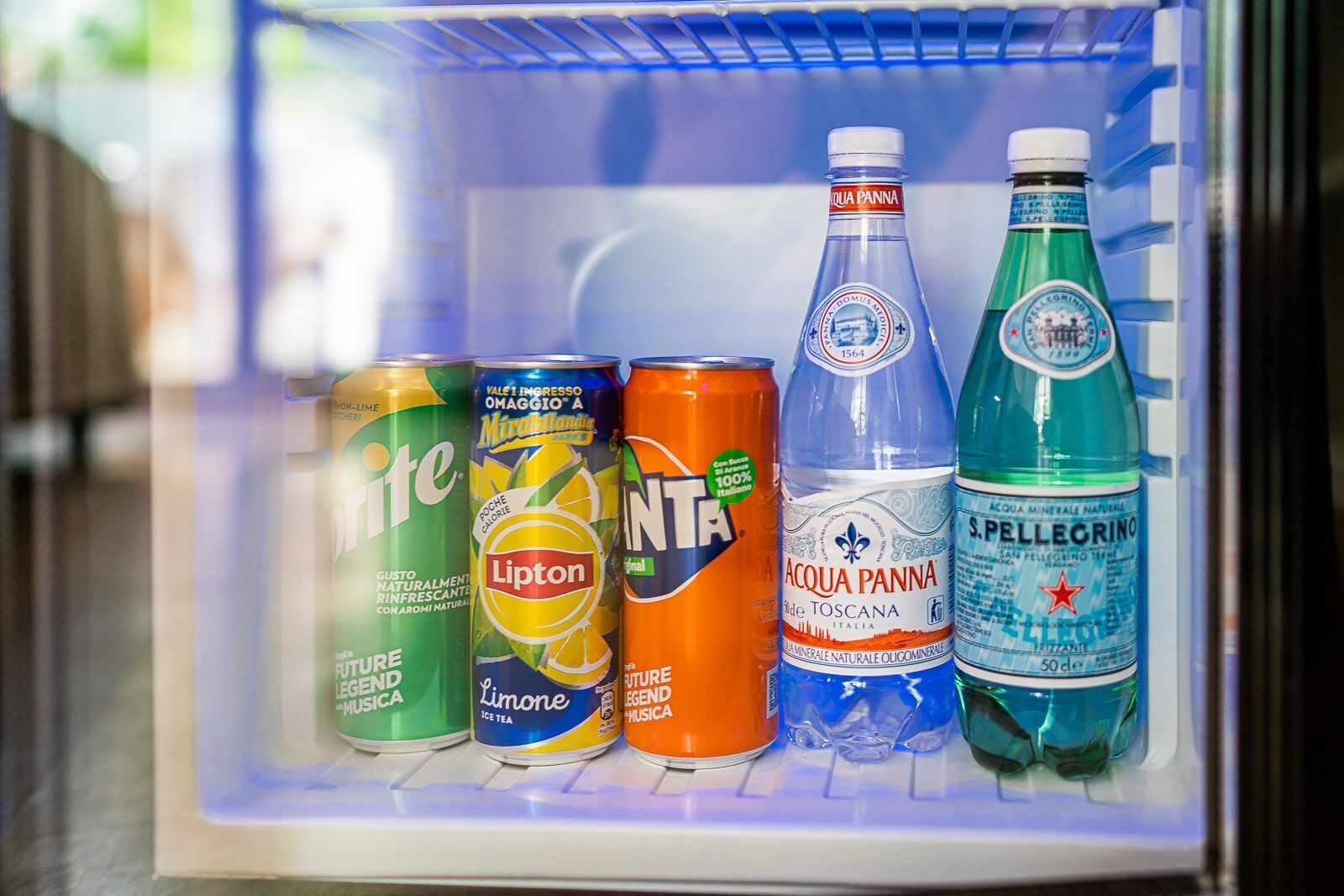 A refrigerator containing various beverages including soda cans and bottled water.