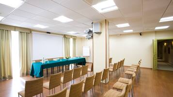 A conference room with a long table, chairs, a projector, and a whiteboard.