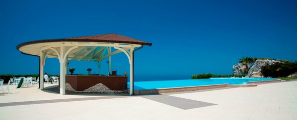 A gazebo with a tiled floor and a pool in the background.