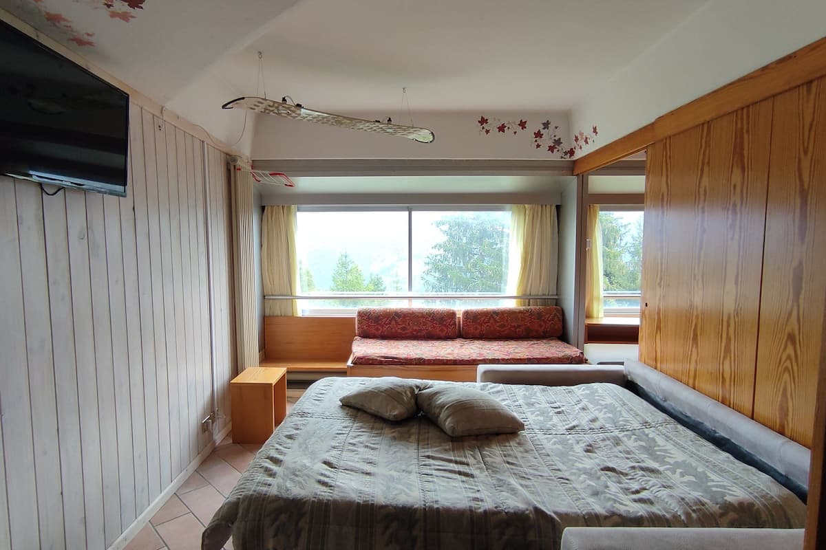 A bedroom with a bed, a bench, and a window.