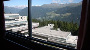 A view from a window overlooking a mountainous landscape with snow-capped peaks and a forested valley. - Residence Sole Alto (Mezzana)
