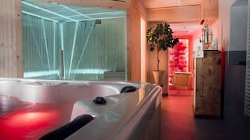 Relax in a serene spa room with a large hot tub, wooden paneling, and a potted plant.