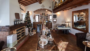 A cozy interior with a wooden ceiling, a brick fireplace, a Christmas tree, and a bar area with wine bottles. - Il Castelluccio Country Resort (Barberino di Mugello)
