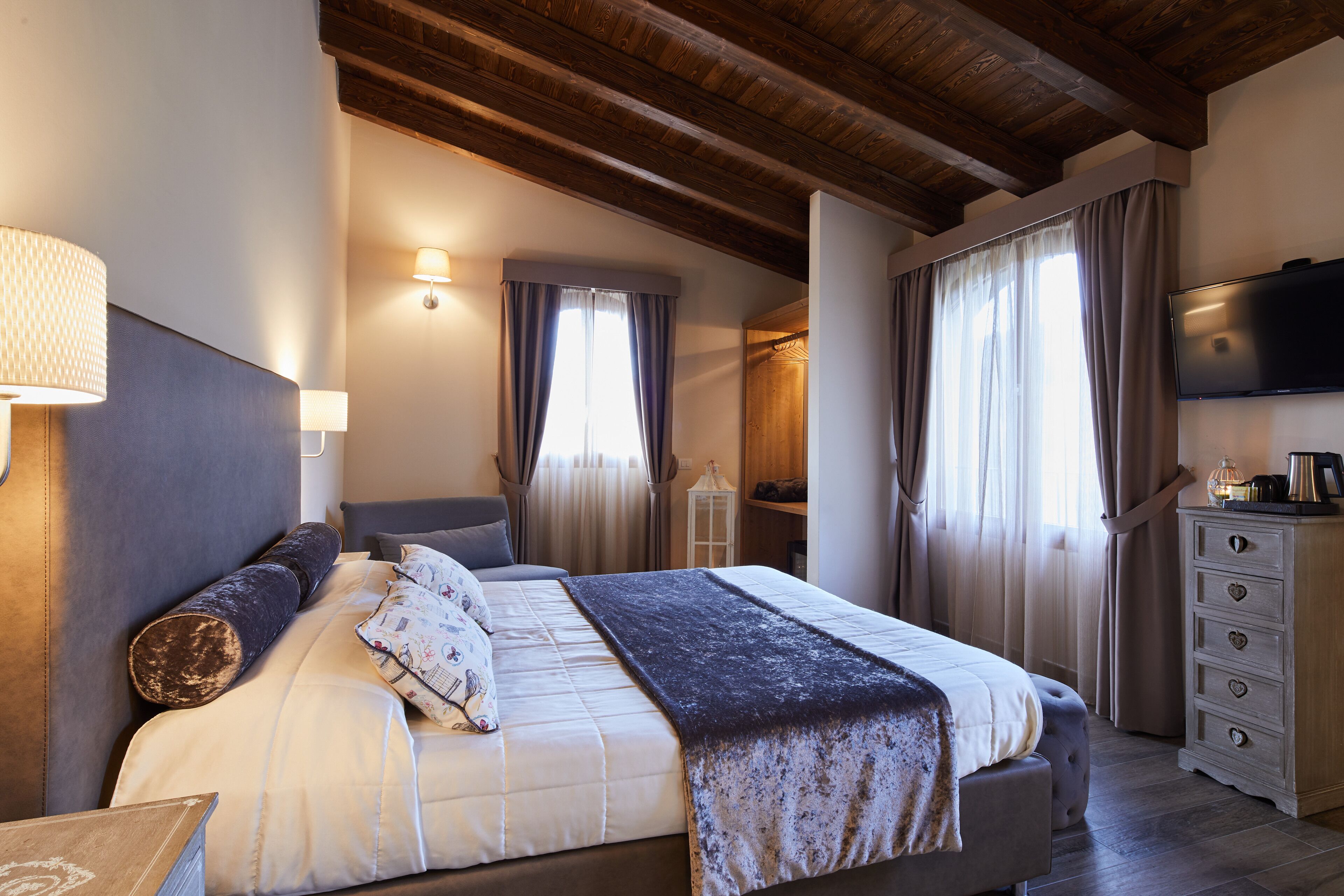 Une chambre à coucher avec un lit, des lampes de chevet, une télévision et une commode.