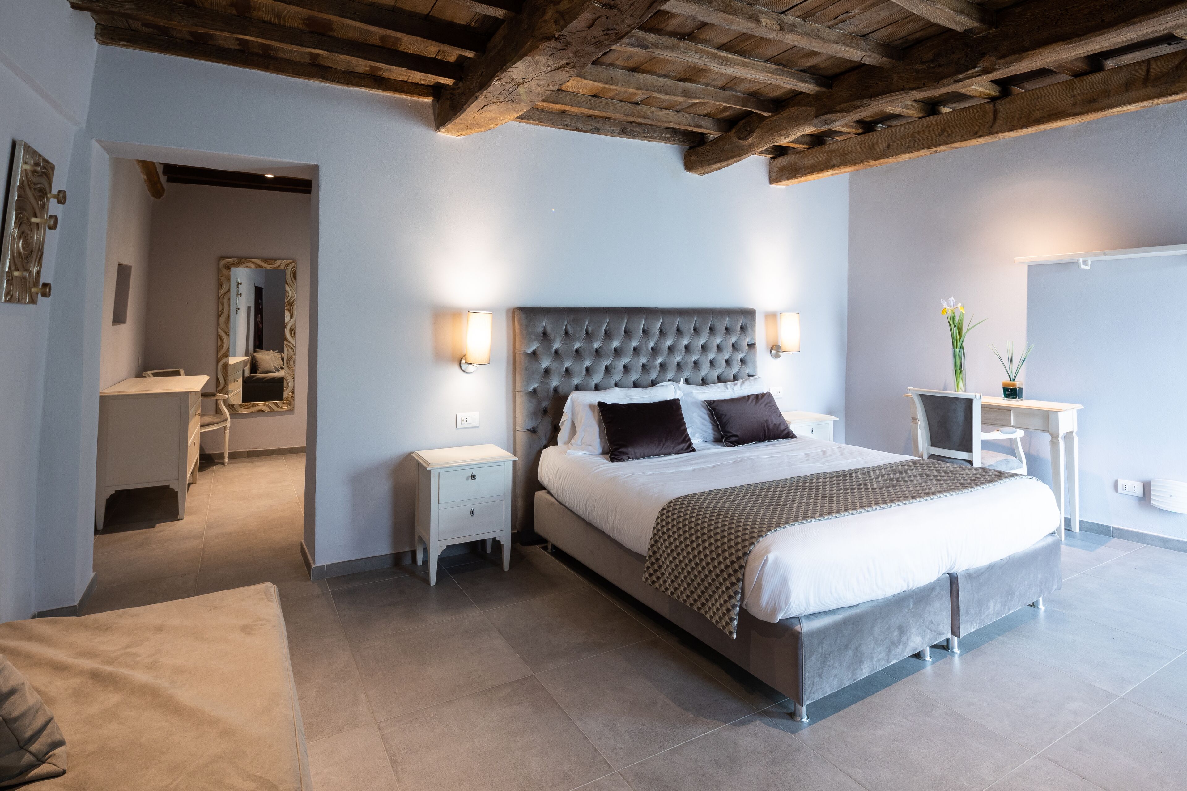 Ein Schlafzimmer mit einem großen Bett, Nachttischen, einem Schreibtisch und einem Spiegel.