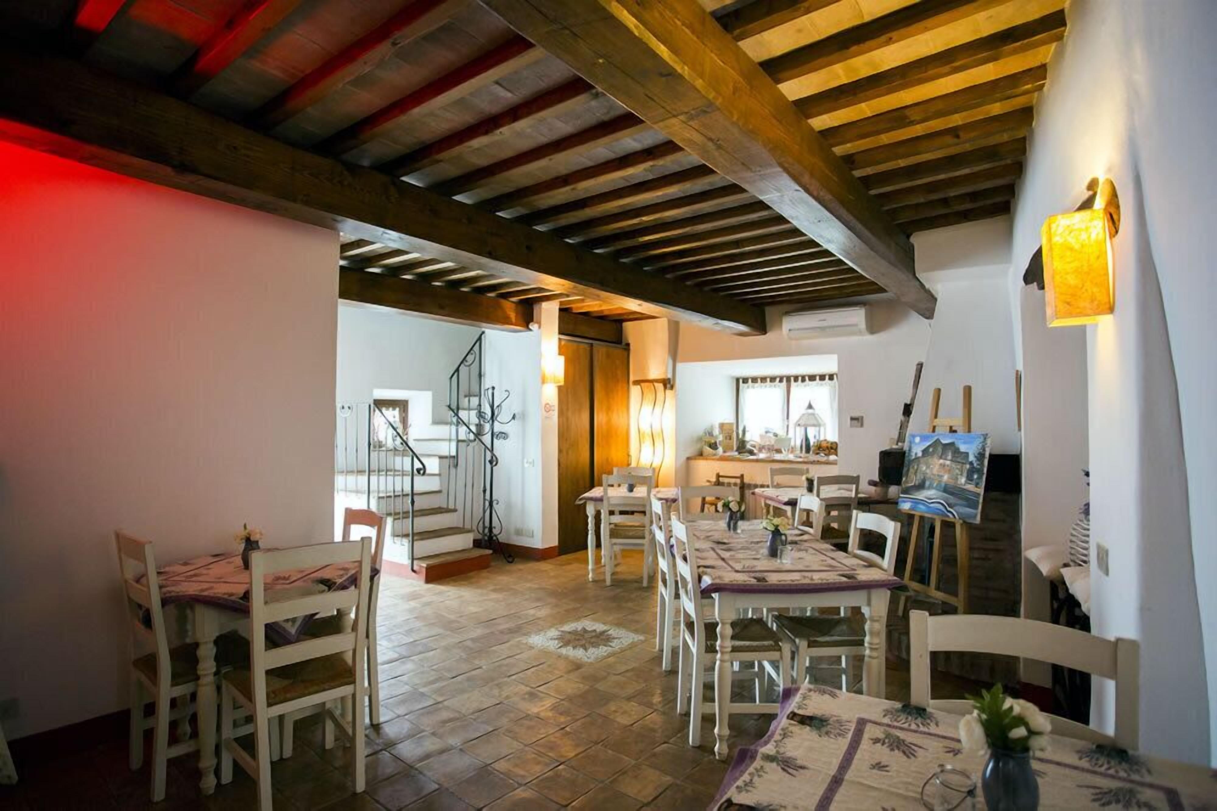 A dining area with wooden beams, a staircase, and a painting on the wall.
