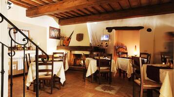A cozy dining area with wooden beams, tiled flooring, and tables set for dining.