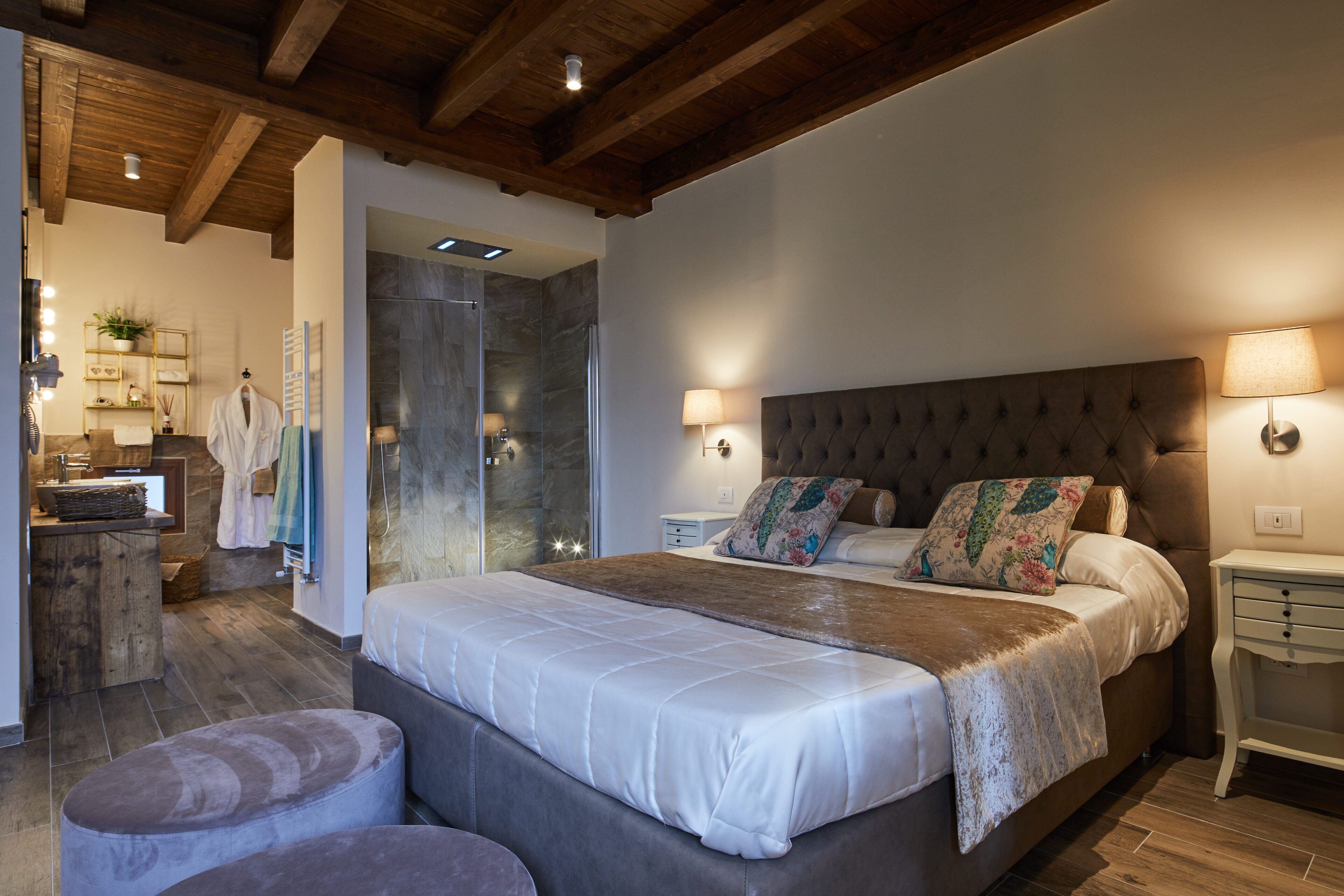 A bedroom with a large bed, bedside lamps, a wooden headboard, and a small bedside table.
