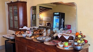 Un bufé de desayuno con diversos alimentos, un aparador de madera y un refrigerador al fondo.