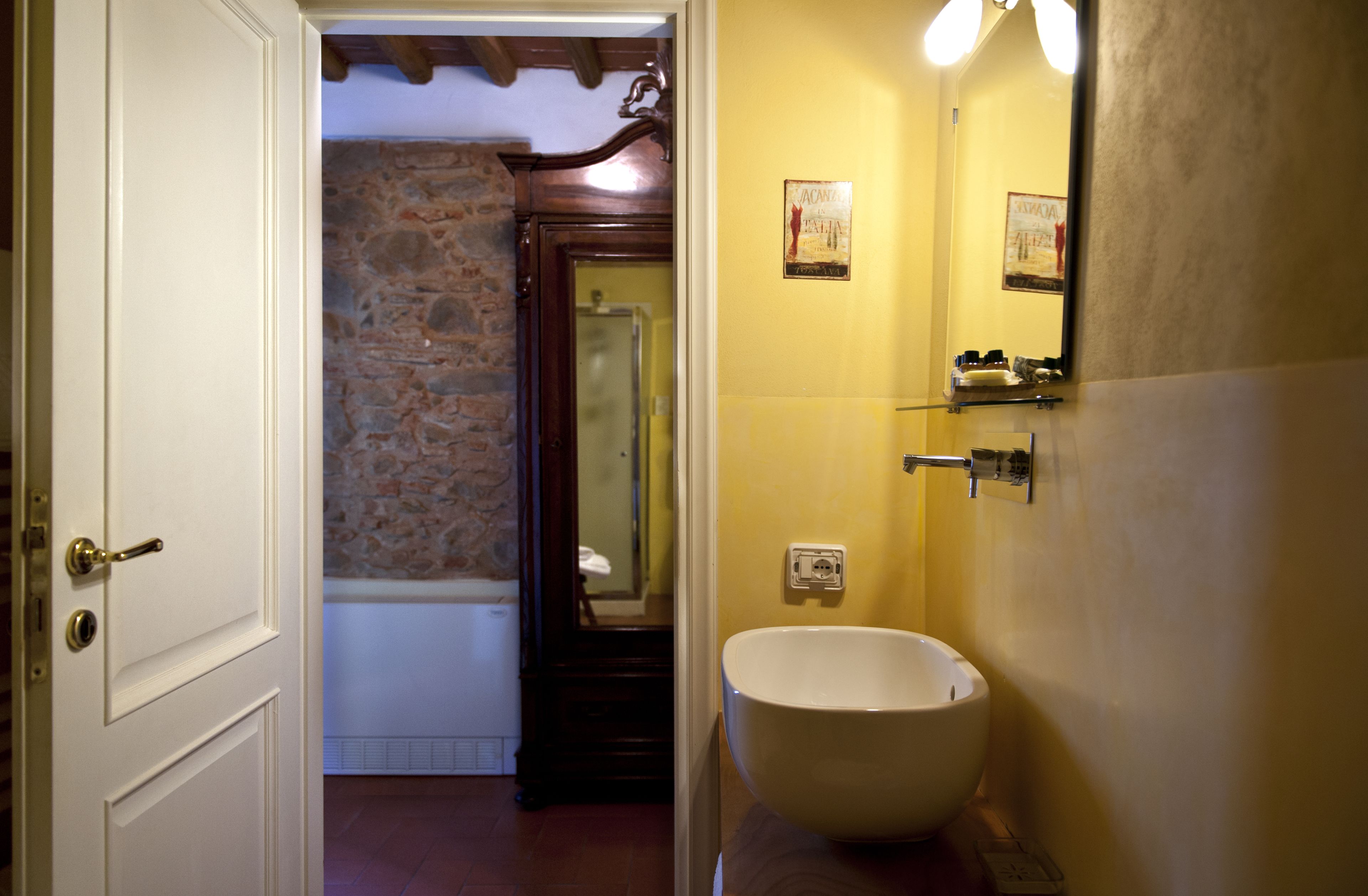 A bathroom with a stone wall, a bathtub, a white sink, and a mirror.