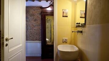 A bathroom with a stone wall, a bathtub, a white sink, and a mirror.