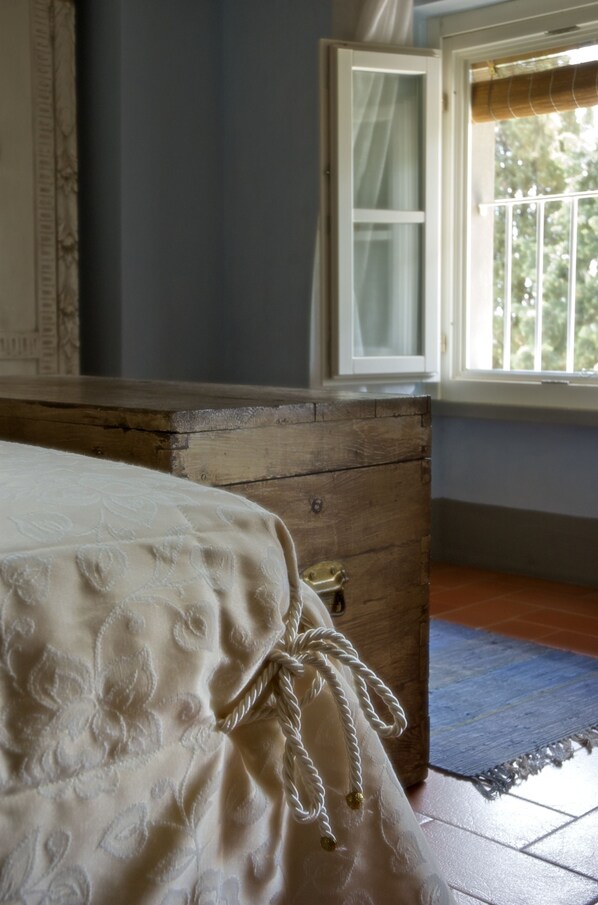 A bedroom with a wooden dresser, a bed with a white bedspread, and a window with curtains.