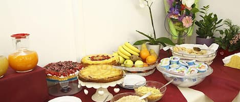 Una mesa de buffet con diversos alimentos, como frutas, postres y bebidas.