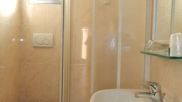 Un baño con inodoro, lavabo y cabina de ducha.