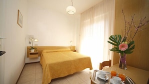 A hotel room with a bed, bedside table, lamp, and a breakfast tray with cups and juice. - Hotel Sport (Rimini)
