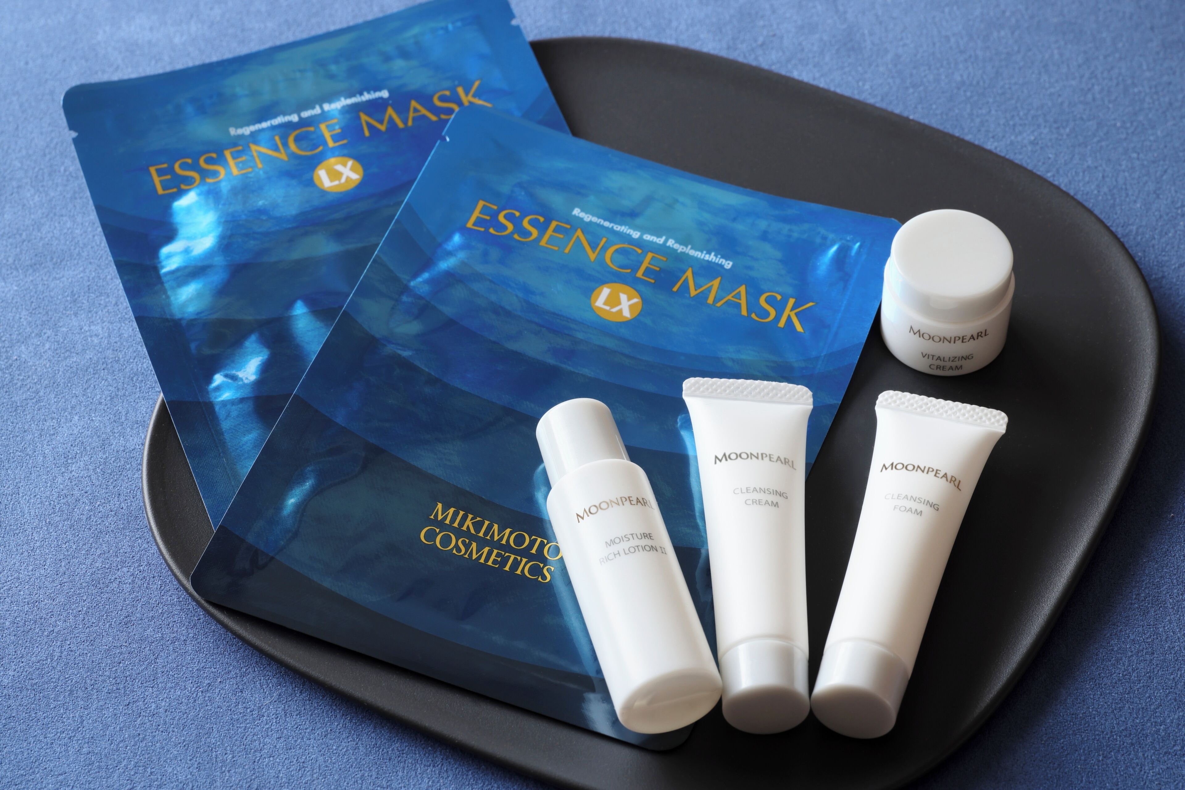 A tray with a blue package labeled 'ESSENCE MASK' and three tubes of 'MOONPEARL' skincare products.