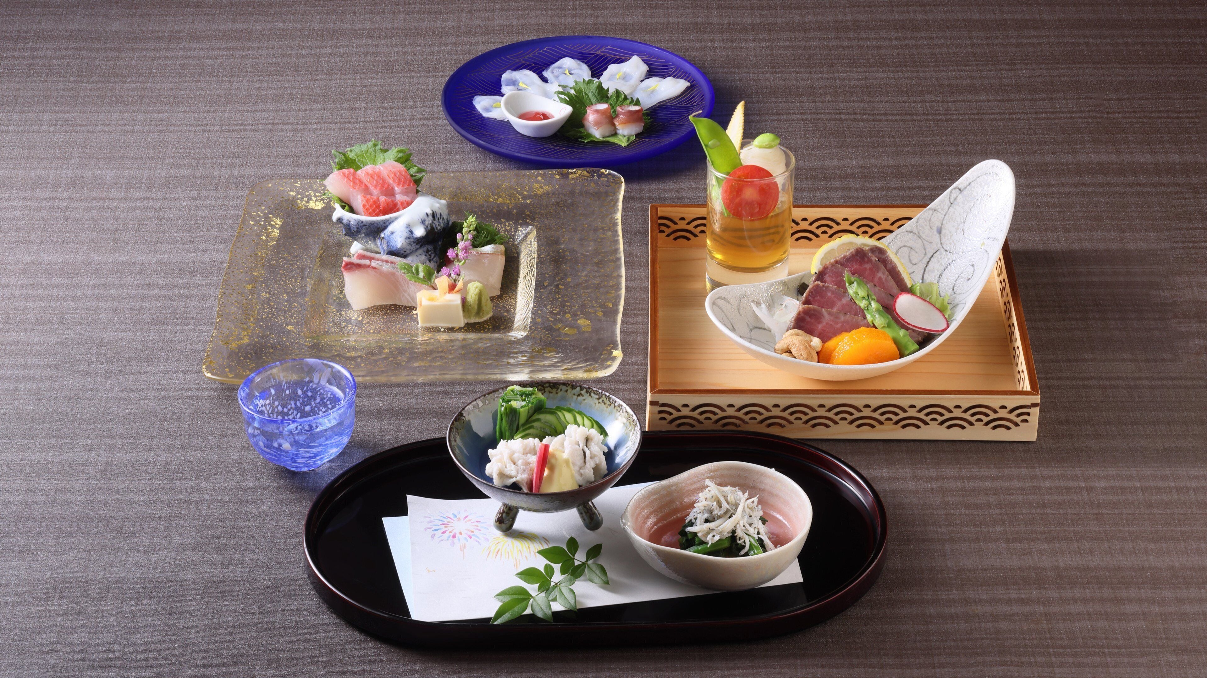 A variety of Japanese dishes on a table, including sushi, sashimi, and a bowl of vegetables.