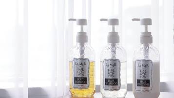 Three bottles of Lamer by Thai Goja Pon shampoo and conditioner on a table.