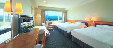 Quarto de hotel com duas camas, uma escrivaninha, televisão e janela com vista para as montanhas.