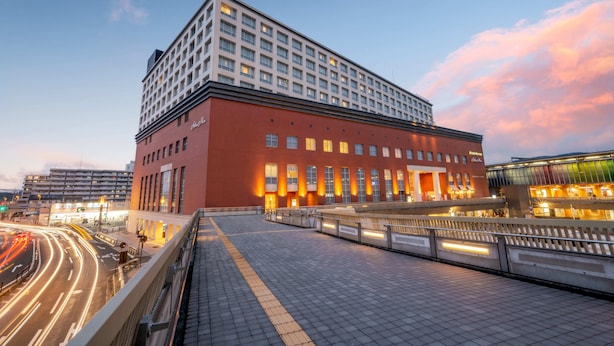 A modern hotel with a red facade, multiple floors, and a large entrance area with a covered walkway. - Hotel Nikko Nara (Nara)
