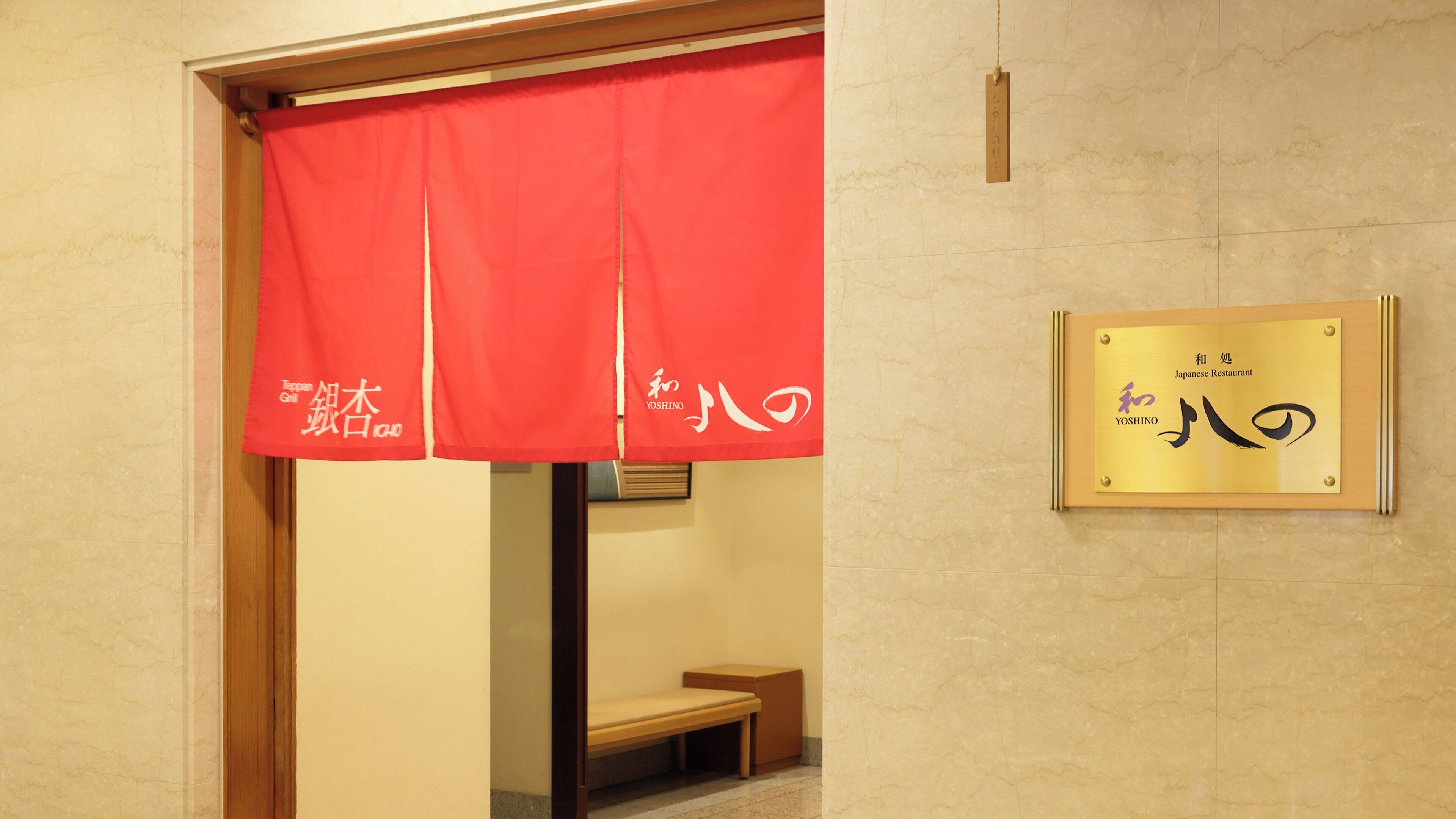 A Japanese restaurant entrance with a red curtain and a gold plaque with Japanese characters.