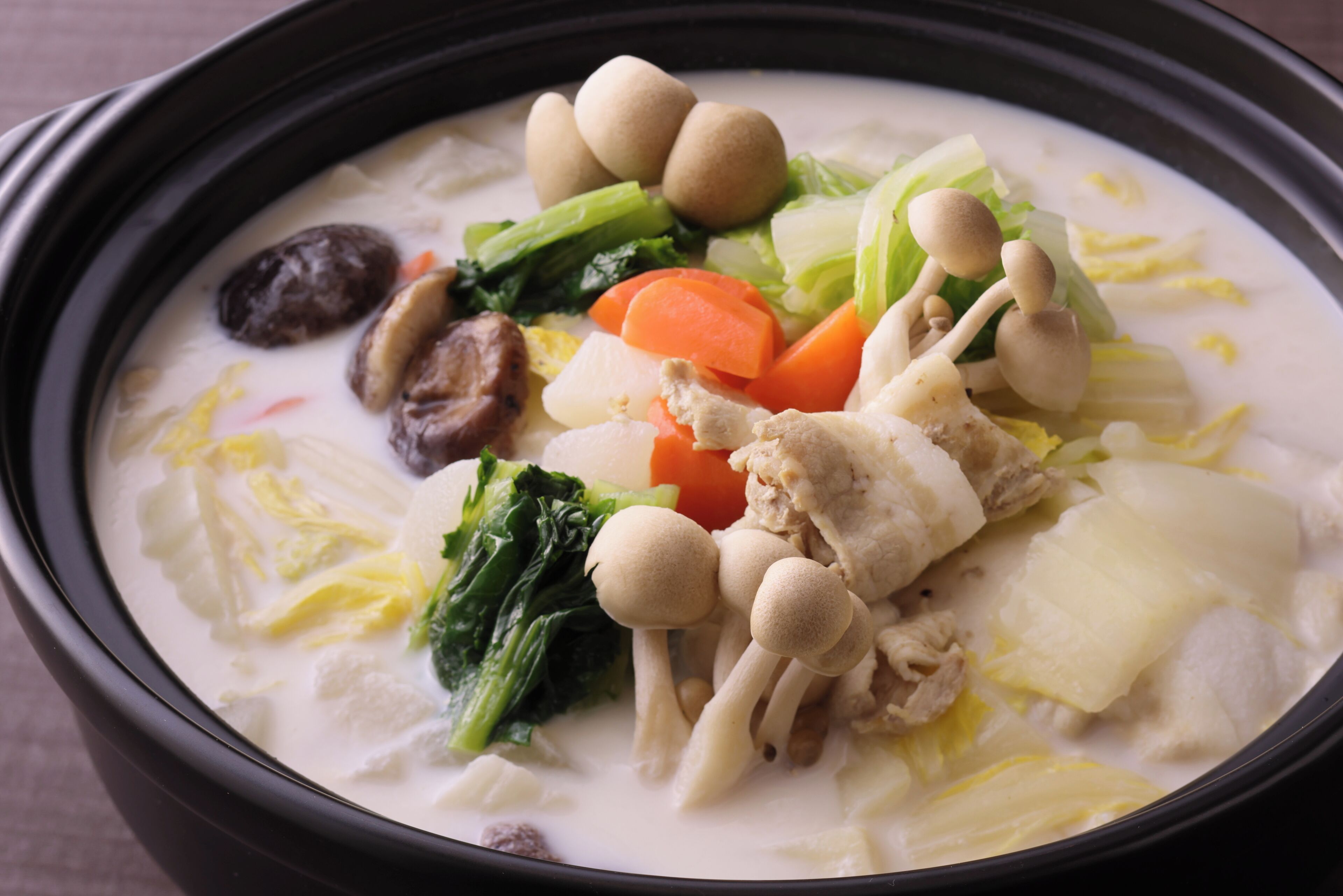 A bowl of soup with various vegetables and mushrooms.