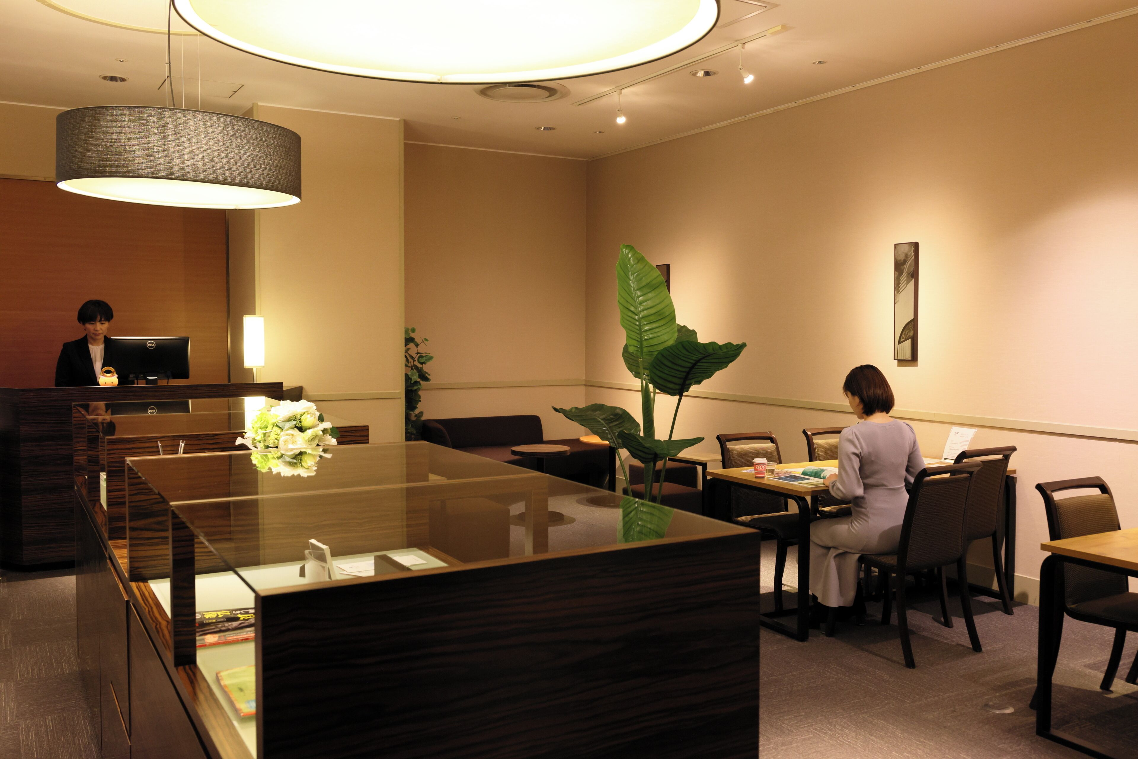 A reception area with a reception desk, seating area, and a large plant.