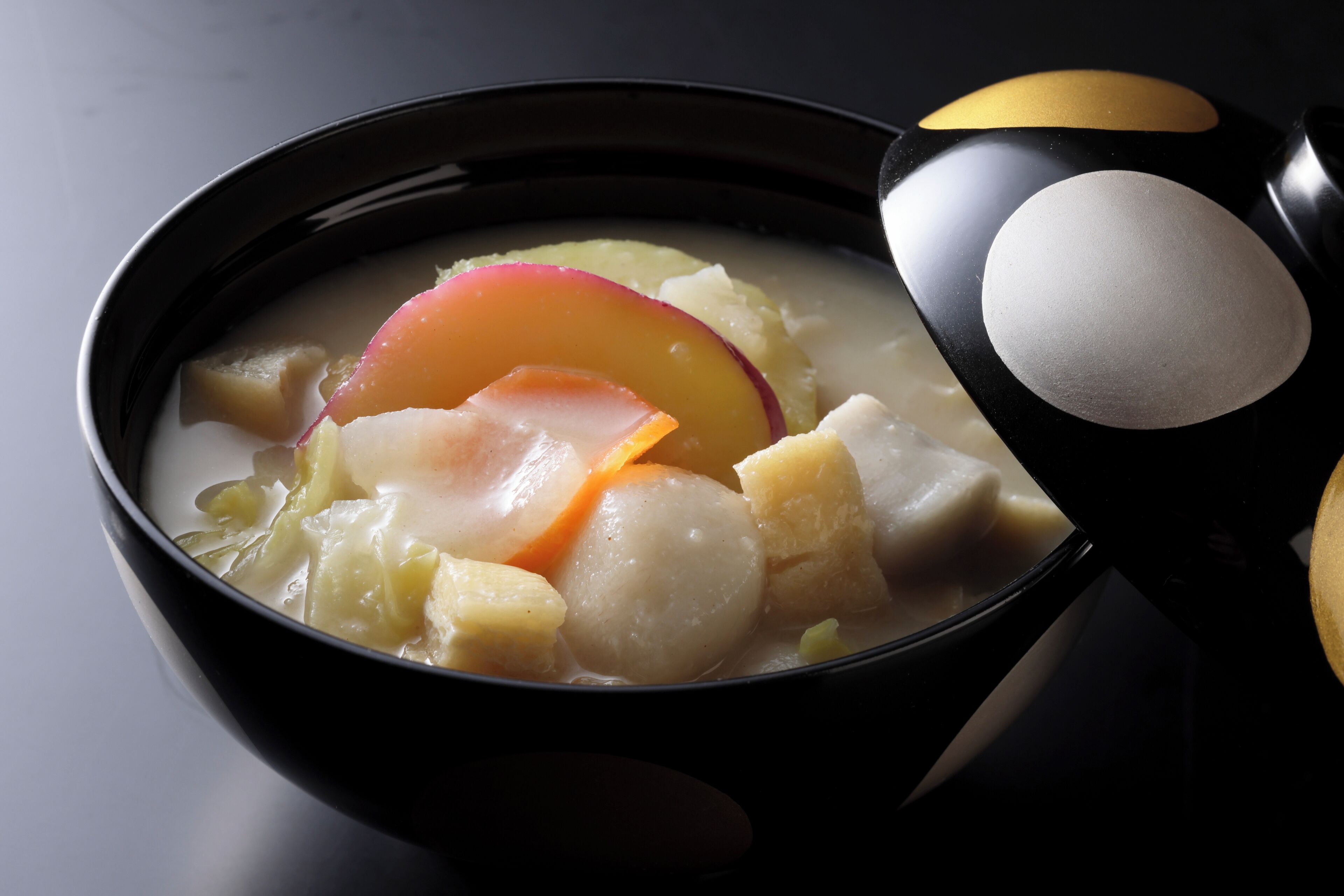 A bowl of soup with various vegetables and a spoon.