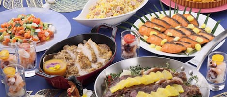 Una mesa con varios platos, incluyendo sushi, una tarta de frutas y un bol de arroz con carne.