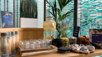 A bar area with a variety of glasses, a large pitcher, and a selection of snacks and fruits.