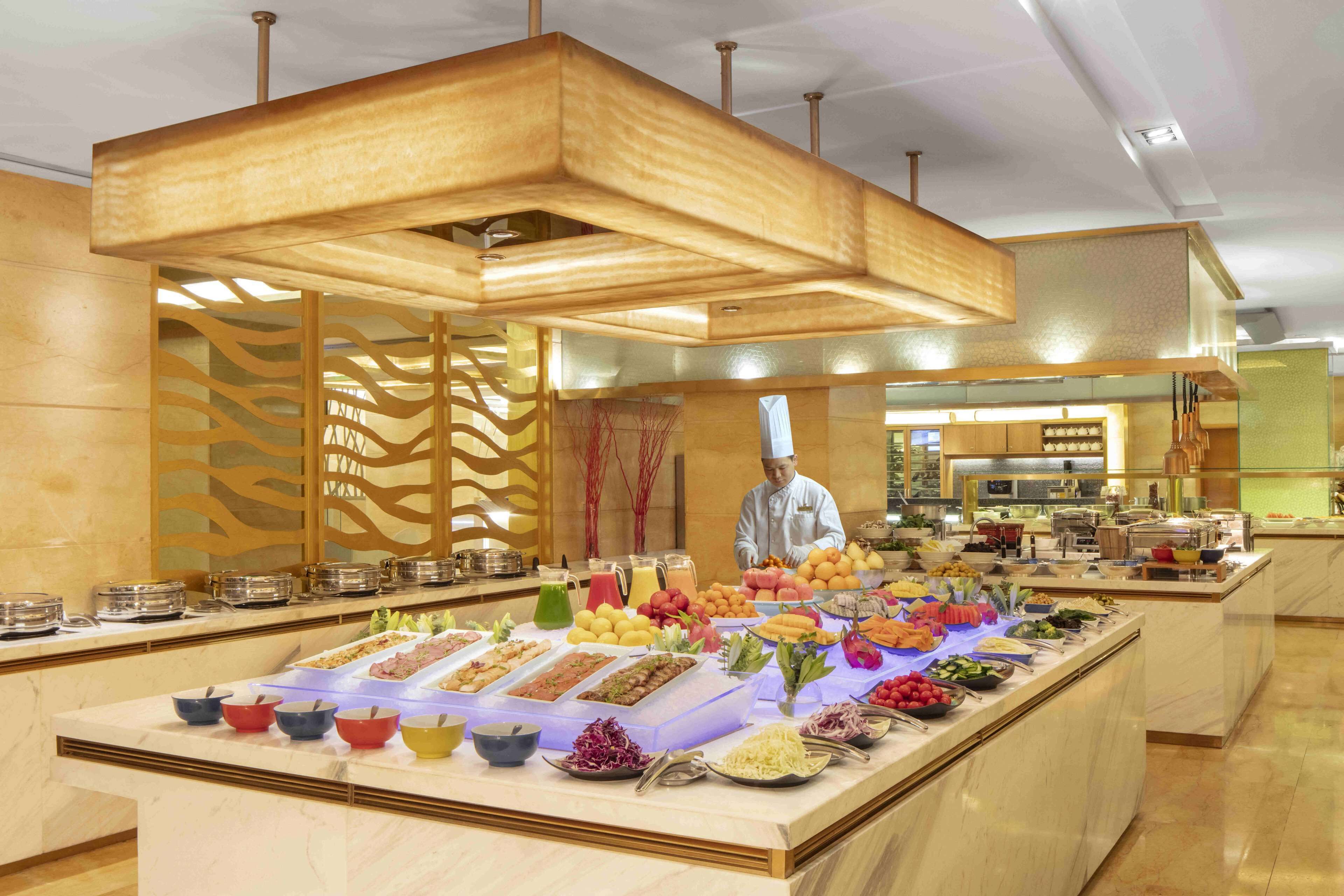 A buffet with various food items and a chef in the background.