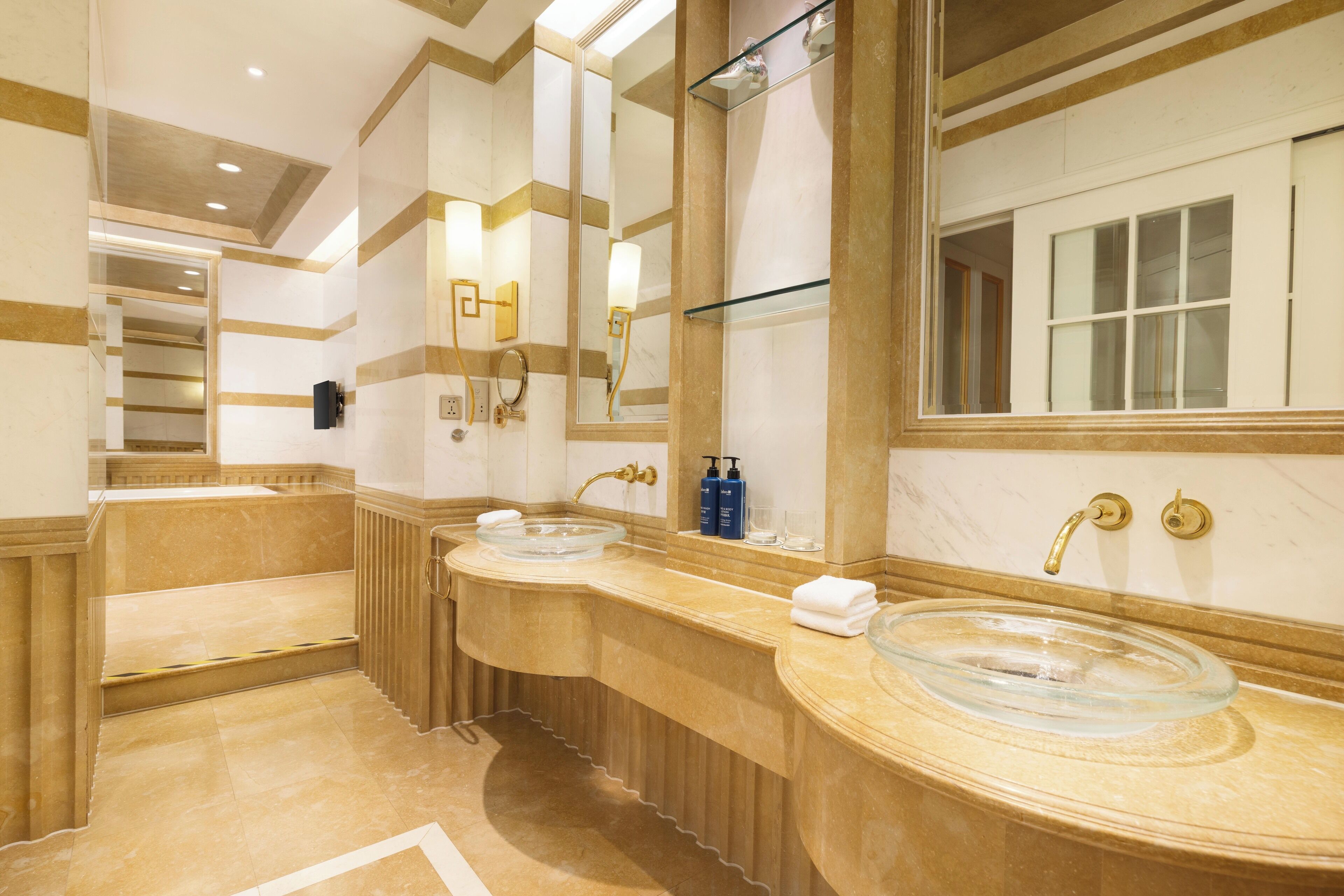 Ein Hotelbad mit zwei Waschbecken, einem großen Spiegel und einer Glaskabinentasse.