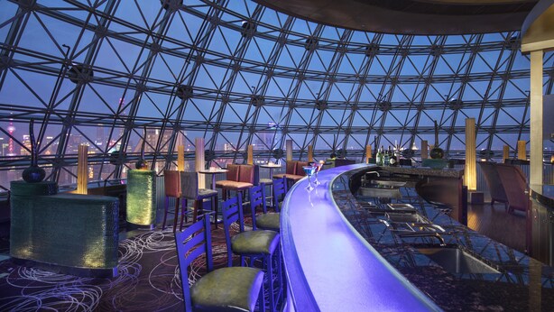 A modern bar area with a high ceiling and a glass dome structure, featuring seating and a bar counter. - Radisson Blu Hotel Shanghai New World (Shanghai)