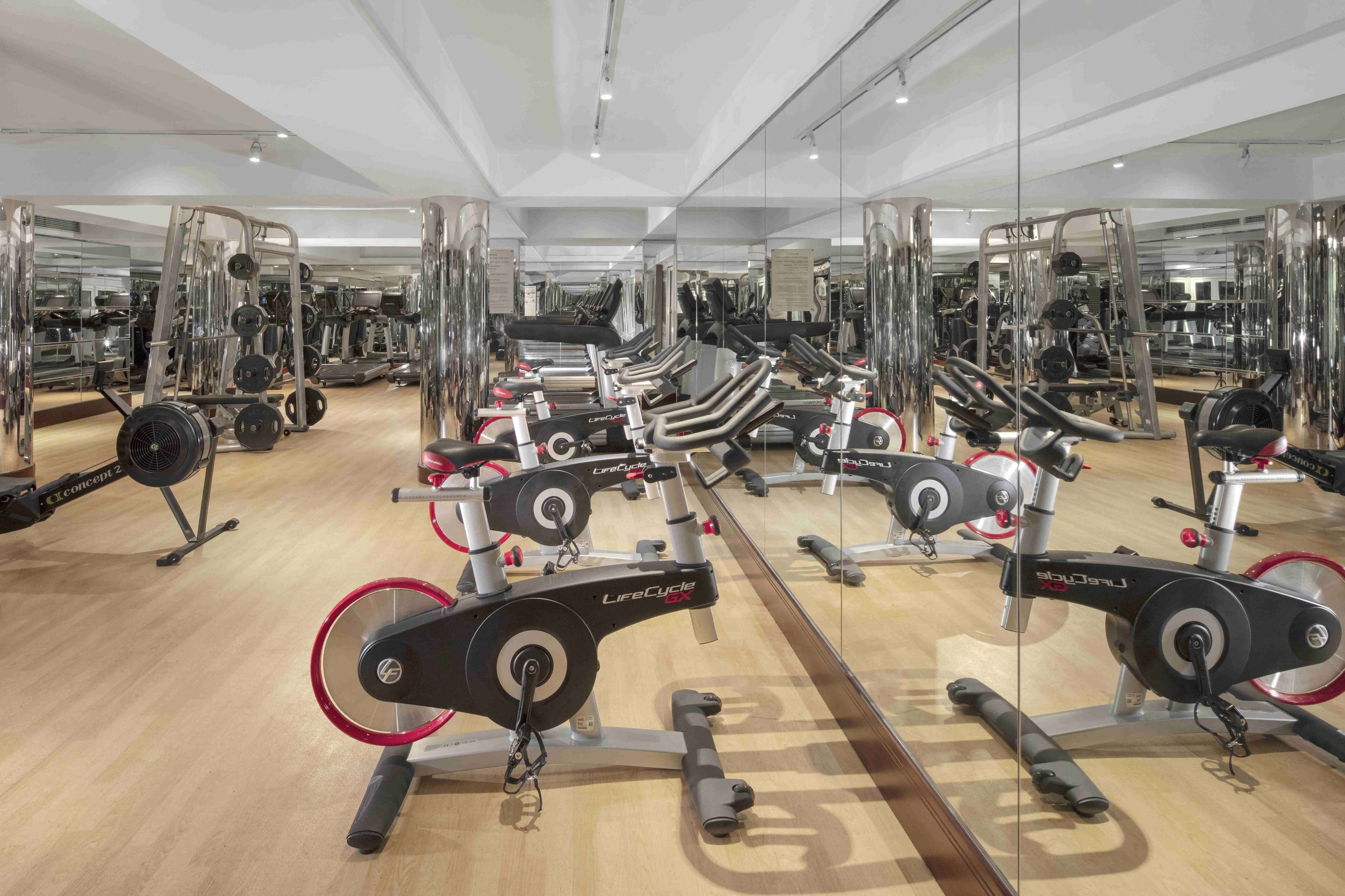 A gym with multiple exercise machines, including treadmills and weight machines, arranged in rows.