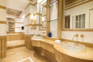 A bathroom with two sinks, a large mirror, and a glass-enclosed basin.