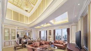 A spacious living room with a high ceiling, a chandelier, and a city view through large windows. - Radisson Blu Hotel Shanghai New World (Shanghai)