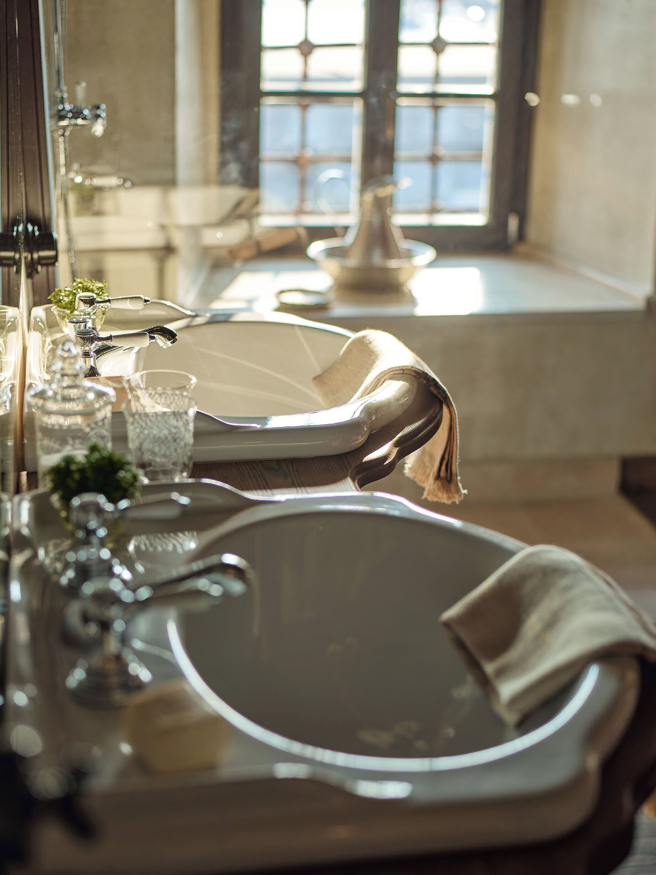A bathroom with a large, round mirror, a sink, and a window with a view of the outside.