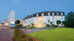 Un hôtel à la façade incurvée, doté de nombreuses fenêtres et d’une pelouse bien entretenue.