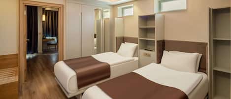 A hotel room with two beds, a wardrobe, a mirror, and a small seating area.