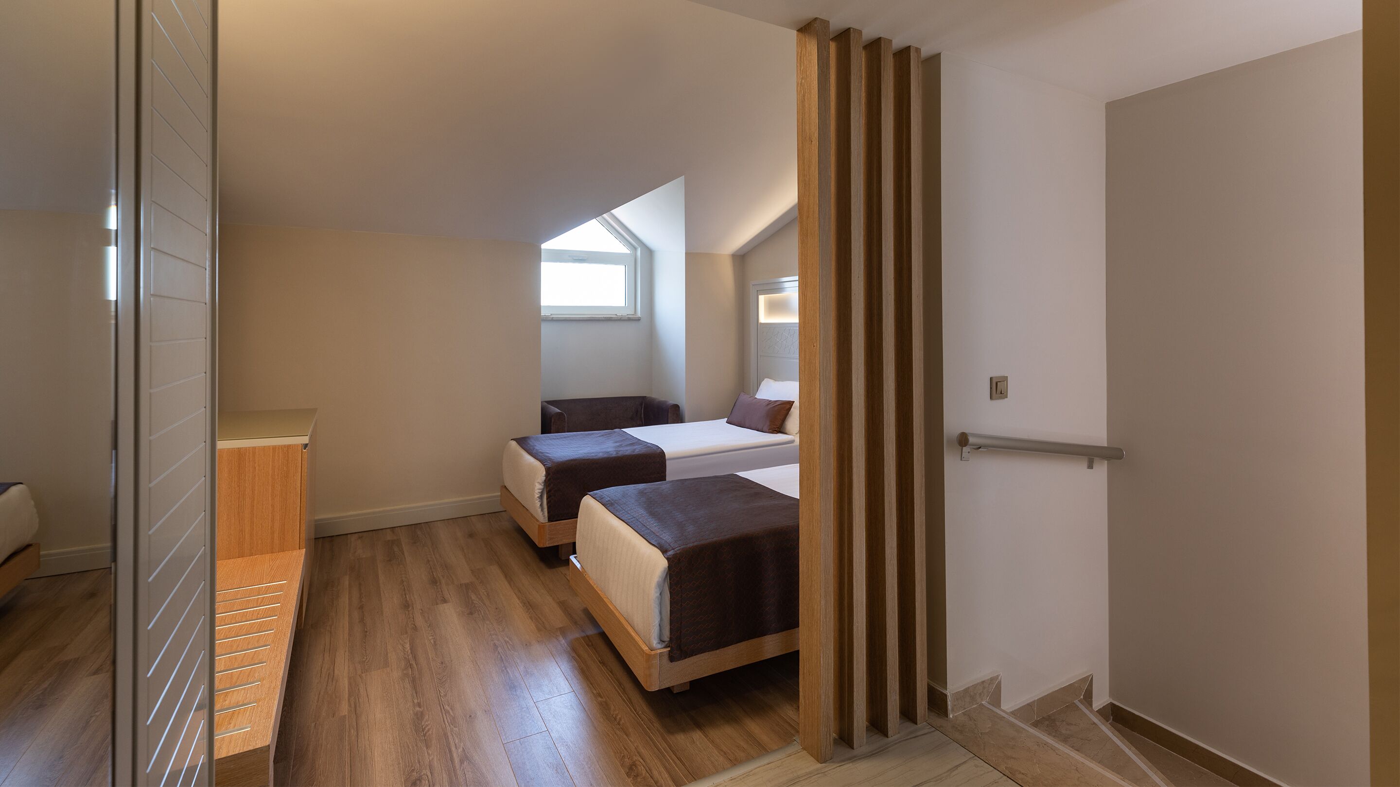 Ein Schlafzimmer mit zwei Betten, Holzboden, einem Fenster und einer Tür.